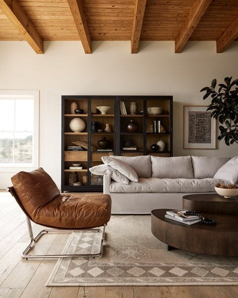 Avett Coffee Table from Four Hands in smoked guanacaste - styled with a leather chair and grey sofa