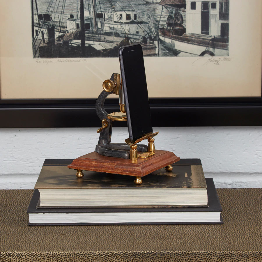 Microscope stand styled on a desk holding a phone